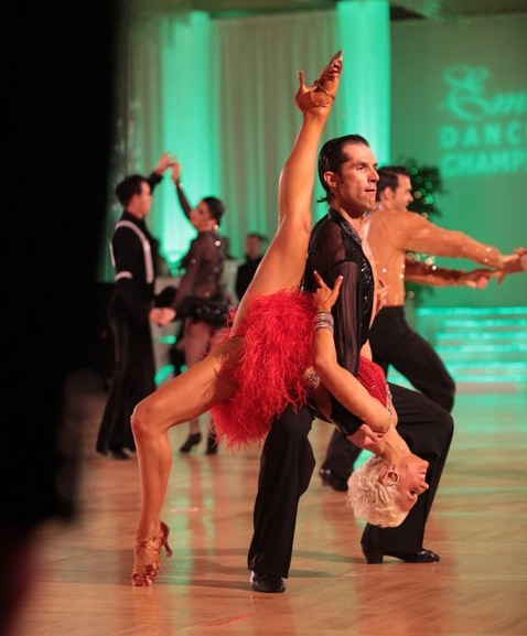 Bree Watson performing a leg extension in red ballroom dress